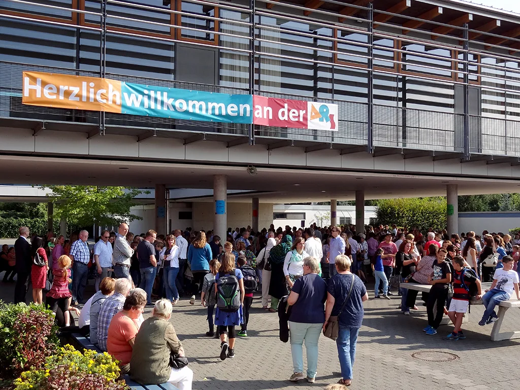 Banner „Herzlich willkommen an der“ über dem Schulhof voller Familien.